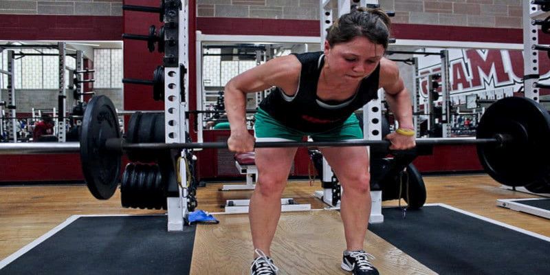 Picture of a woman performing bent over barbell rows in the gym.
