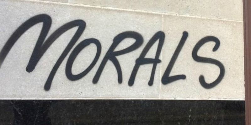 Image of the word “morals” written against a wall.