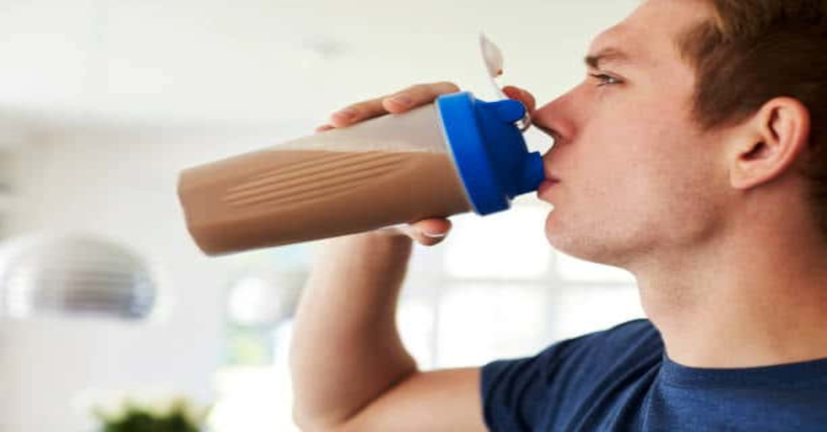 Picture of a man drinking a protein shake at home.