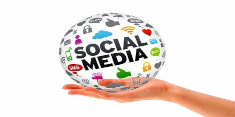 Image of a hand holding a ball with in the middle written, “social media”, and with various emblems of social media platforms surrounding it.