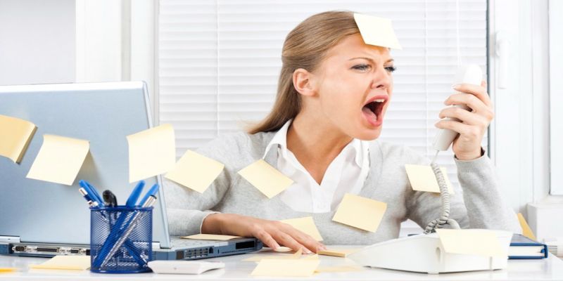 Image of a stressed woman yelling in a phone, with multiple post-it notes sticking on her clothes and table.