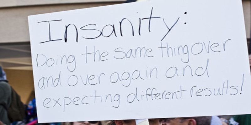 Image of a sign saying, “insanity, doing the same thing over and over again and expecting different results”.
