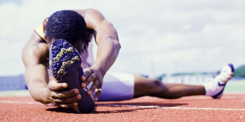 Picture of a man performing static stretching exercises on a track.