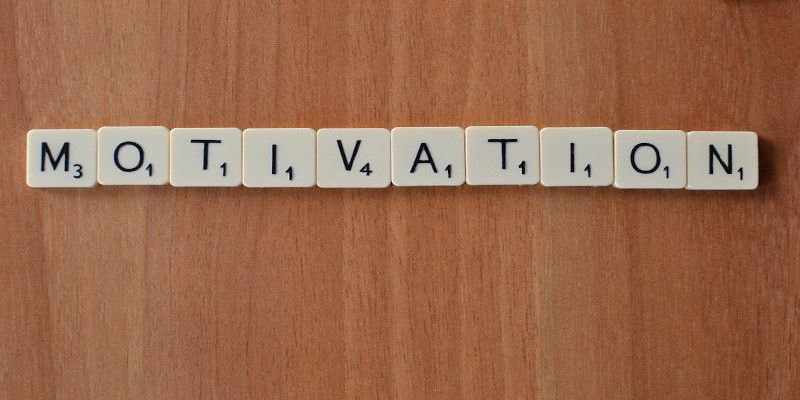 The word, 'motivation', written with small scrabble blocks on a wooden table.