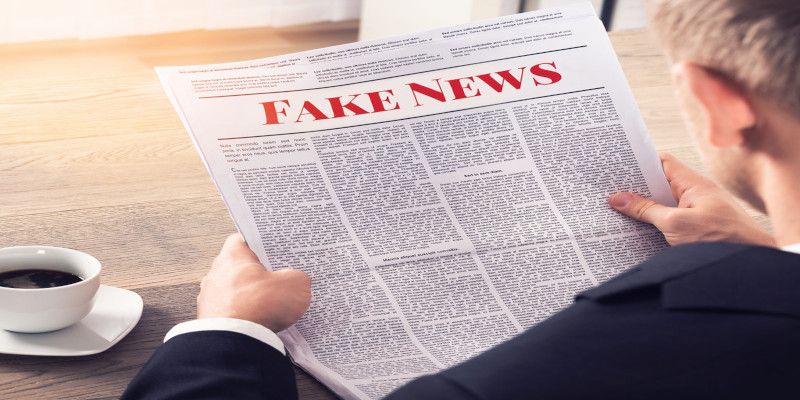 Image of someone holding a newspaper reading, 'fake news' as the heading.