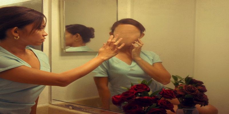 A woman suffering from an episode of depersonalization/derealization disorder in the mirror.