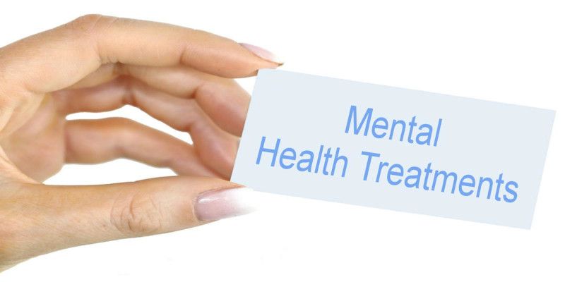 Image of a woman's hand holding a card reading, 'mental health treatments'.