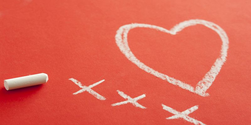 Love and kisses with a symbolic drawing of a heart with three crosses drawn in chalk on a red background with copy space for your Valentine greeting.