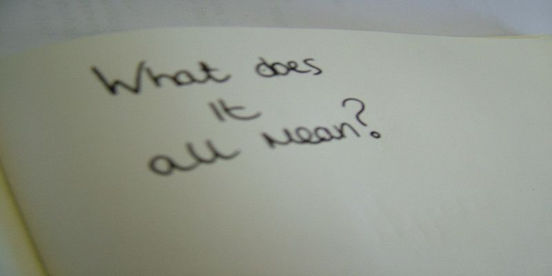 Image of the sentence, “what does it all mean?” Written on a white piece of paper in black ink.