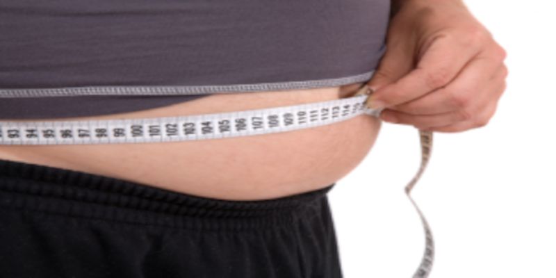 Image of a man measuring his waist while having excess belly fat.