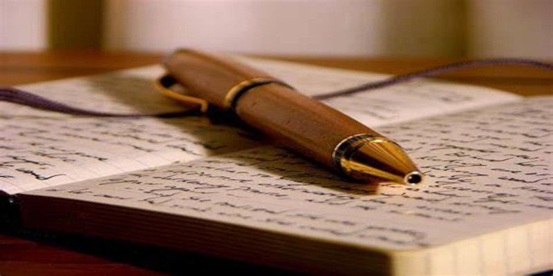 Image of a pen lying on top of a notebook.