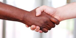 Image of a person of white and black skin color holding hands.
