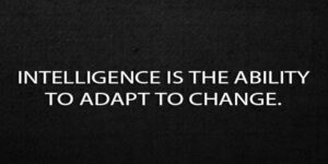 The quote, “intelligence is the ability to adapt to change” written in white letters on a black background.