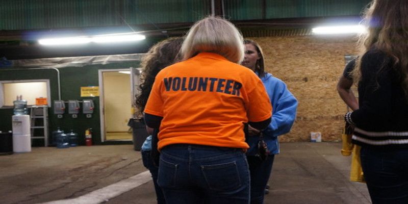 Image of the rearview of a woman wearing an orange shirt saying “volunteer”.