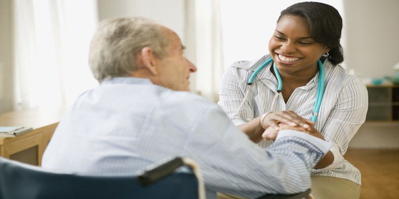 Image of a dark skinned medical practitioner conversing with her patient while smiling.