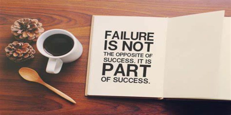 The quote, “failure is not the opposite of success. It is part of success.” Written in black letters in an open book lying on a wooden table with a cup of coffee beside it.