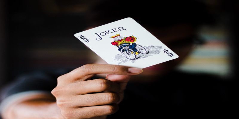 Image of someone's hand holding up a joker card.